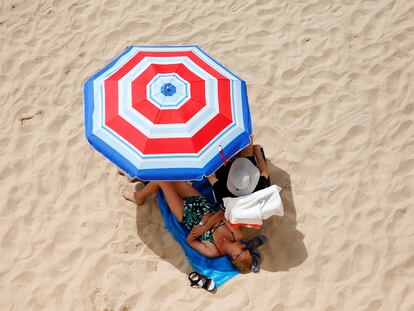 Dos turistas disfrutan del sol en la playa de Levante de Benidorm.