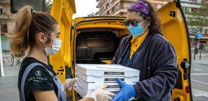 La empleada de la pizzería Del Poble Itziar Úbeda, entrega a una voluntaria de Correos las pizzas realizadas para Food4heroes