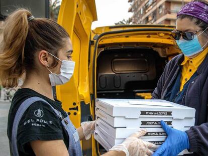 La empleada de la pizzería Del Poble Itziar Úbeda, entrega a una voluntaria de Correos las pizzas realizadas para Food4heroes