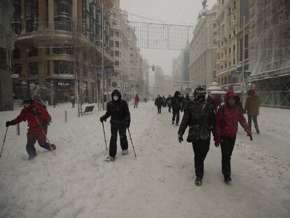 Varias personas, algunas con esquís, caminan por el centro de la Gran Vía, en Madrid, este sábado.