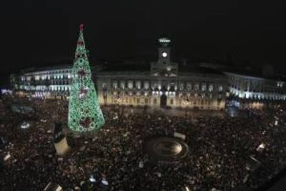 Miles de personas se han concentrado en la madrileña Puerta del Sol bajo la lluvia para tomarse las uvas y celebrar la entrada del Nuevo Año.