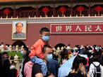 FIEL - In this May 3, 2021, file photo, a man and child wearing masks visit Tiananmen Gate near the portrait of Mao Zedong in Beijing. China’s ruling Communist Party is looking at allowing easing birth limits further to allow couples to have three children instead of two in response to the population's rising age, a state news agency said Monday, May 31, 2021. (AP Photo/Ng Han Guan, File)