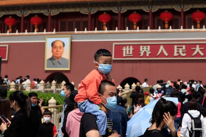 Un hombre y un niño con mascarillas visitan la entrada a la Ciudad Prohibida, en Pekín.