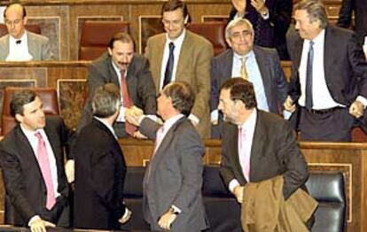 El ministro Rodrigo Rato felicita al portavoz del PP en la Comisión Gescartera, Vicente Martínez Pujalte, tras la votación del dictamen.