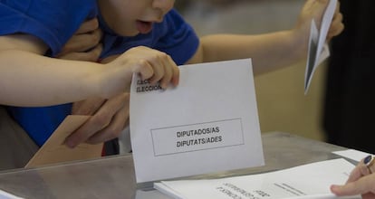 A young boy places a voting slip in Barcelona.