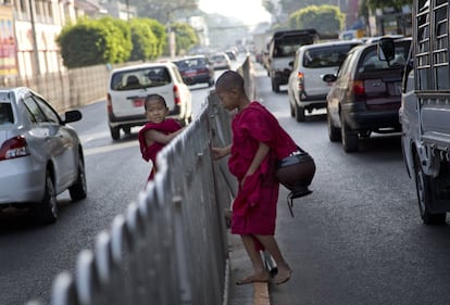 Unos niños budistas intentan cruzar una calle donde piden donaciones en Yangon, Myanmar.