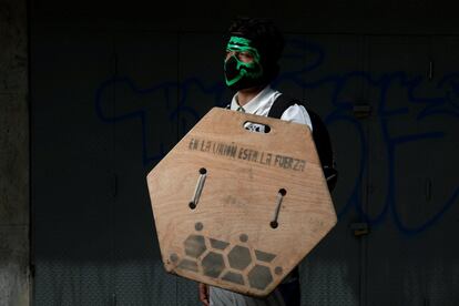 Um participante nos protestos segura seu escudo, fabricado com uma peça de madeira. ‘Este governo não me deu nada. Quero viver bem, comer bem, me vestir bem..., mas o dinheiro que ganho com meu trabalho não permite’.