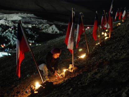 Una familiar de uno de los mineros encerrados enciende velas colocadas junto a banderas chilenas en el exterior de la mina.