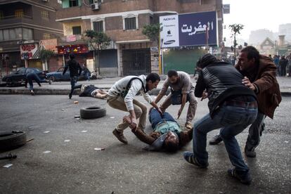 Um partidário do presidente islamista deposto ferido é resgatado por outros manifestantes durante os confrontos com as forças de segurança no distrito Mohandiseen, no Cairo.