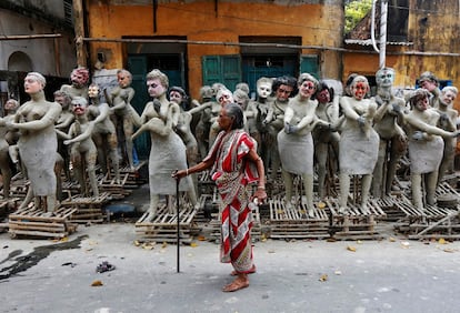 Una mujer camina cerca de dioses de barro no acabados antes del comienzo del festival 'Kali Puka', en Calculta (India). 