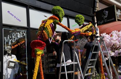 Floristas trabajan en un diseño floral frente a una tienda para participar en el festival floral de Chelsea.
