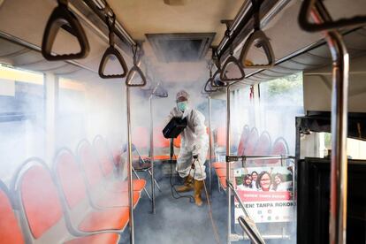 Un trabajador desinfecta un autobús escolar para prepararlo para el traslado de pacientes con coronavirus en Yakarta, Indonesia, este martes. 