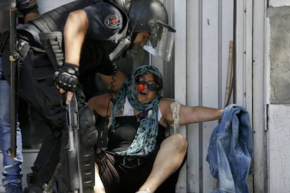 Um policial ajuda uma mulher a se afastar dos confrontos entre manifestantes e agentes nesta segunda-feira nas proximidades do Congresso.