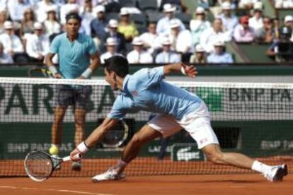 Djokovic estica-se para devolver uma bola a Nadal.