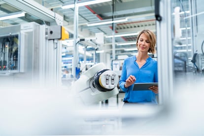 Businesswoman with tablet at assembly robot in a factory