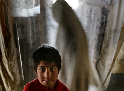 Zalmai, de ocho años, espera detrás de una cortina que hace las veces de puerta de la celda donde ha vivido durante los últimos cuatro años con su madre Parigul, presa por haber abandonado su hogar.