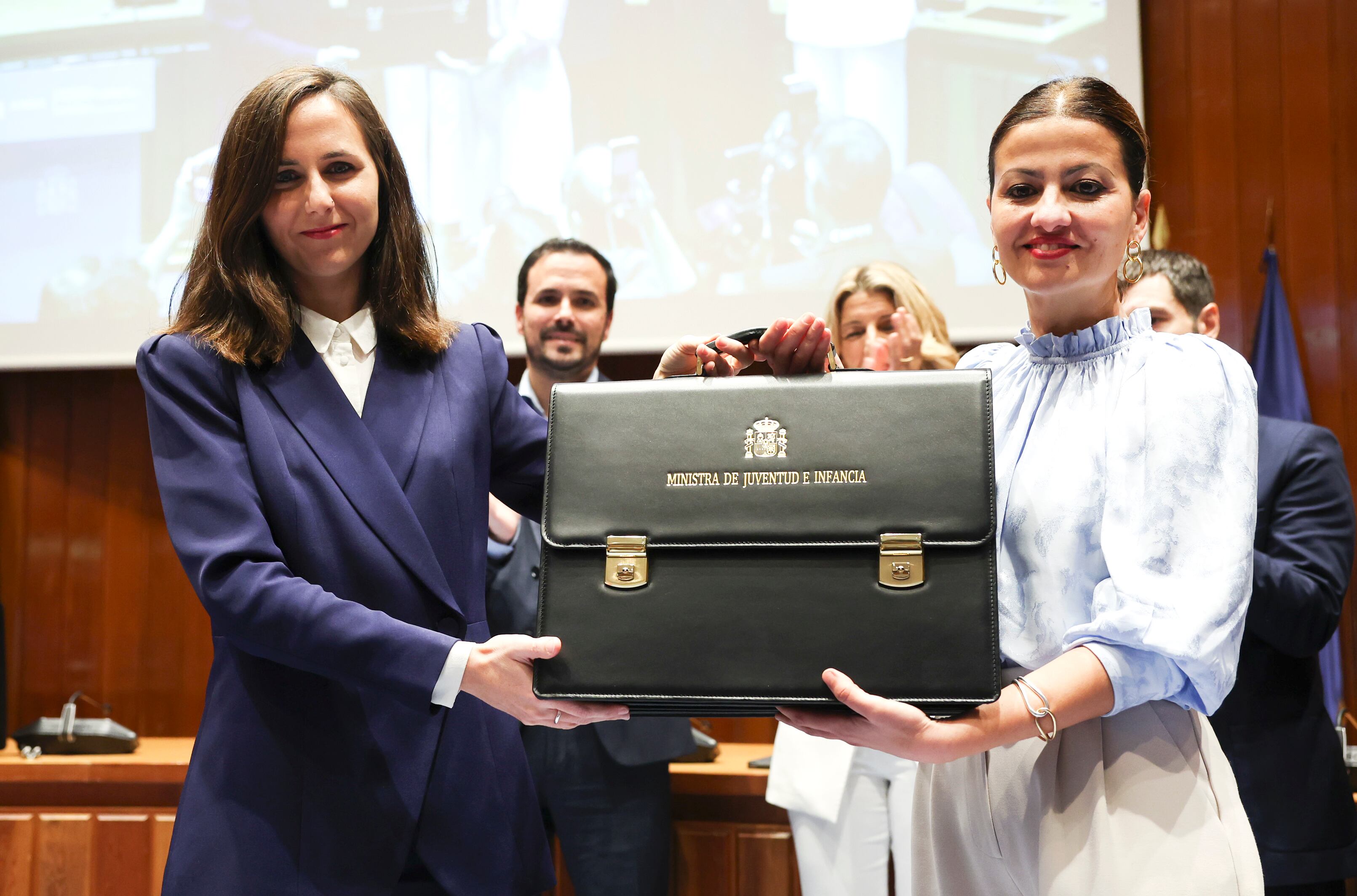 La nueva ministra de Infancia y Juventud, Sira Rego (a la derecha), recibe la cartera de manos de la exministra Ione Belarra, tras tomar posesión de su cargo este martes en la sede del ministerio, en Madrid.