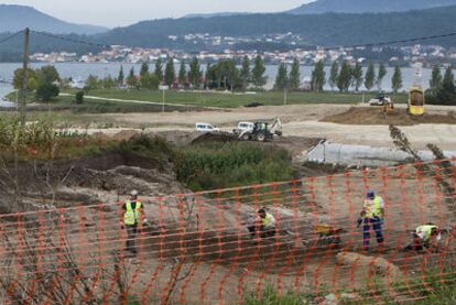 Operarios trabajan en la construcción del vial, con los restos arqueológicos a la vista a la izquierda de la imagen.