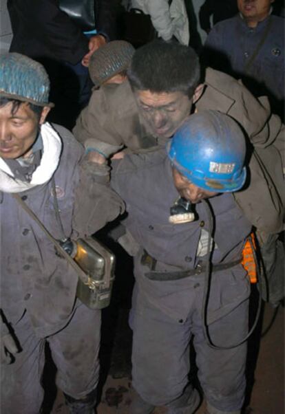 Un minero carga con un compañero herido en la explosión.