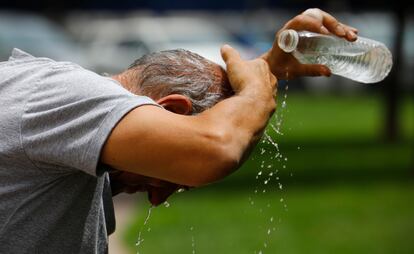 Un hombre se refresca con una botella de agua en el centro de Córdoba.