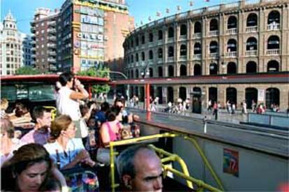 Viajeros del segundo piso del Bus Turístico, a su paso por la plaza de toros de Valencia.