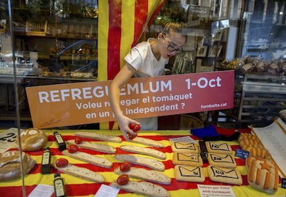 Una empleada de una panadería coloca tomates en un escaparate decorado con elementos del referéndum en Barcelona. La Generalitat y las entidades secesionistas reafirman su intención inamovible de celebrar la votación el domingo 1 de octubre. Creen que ni los golpes judiciales a la logística ni la disolución del ente garante de los resultados ni la suspensión dictada por el Tribunal Constitucional frenarán la cita con las urnas.