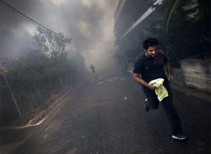 Un hombre escapa del fuego que ha alcanzado la localidad de Agios Stefanos, en las cercanías de Atenas.