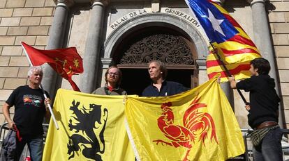 Desde la izquierda: cuatro personas sostienen bandera de Occitania, Flandes, Valonia y la estelada, ante el Palau de la Generalitat