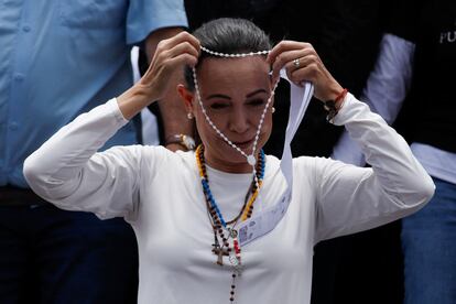 María Corina Machado se coloca uno de los tantos rosarios que le van regalando a su paso.