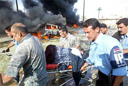 Policías iraquíes trasladan a uno de los heridos por la explosión de un coche bomba en la sede de la Cruz Roja en Bagdad.