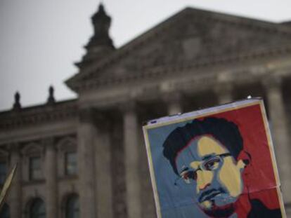 Un hombre porta un cartel de Snowden frente al edificio del Bundestag.