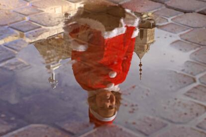 Una niña palestina disfrazada de Papá Noel se refleja en un charco frente a la iglesia San Porfirio de Gaza (Palestina), el viernes.