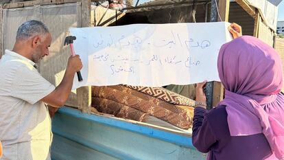 Mahmoud Omar cuelga un cartel a la entrada de una tienda en Al Mawasi, al sur de Gaza, lamentando la destrucción de su casa.