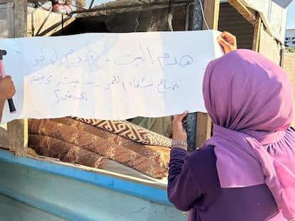 Mahmoud Omar cuelga un cartel a la entrada de una tienda en Al Mawasi, al sur de Gaza, lamentando la destrucción de su casa.