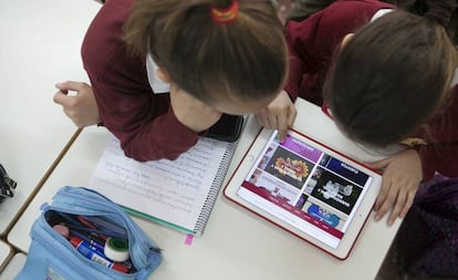 Dos niñas trabajan en clase con una tableta.