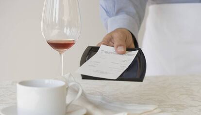 Un camarero retira una factura de la mesa de un bar.