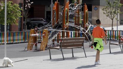 Un menor pasea a su perro junto a un parque cerrado en Bilbao.