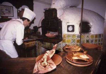 Un cocinero introduce una fuente en el horno de asar de asados de lechazo y cochinillo típicos de la gastronomía de Castilla y León. EFE/Archivo