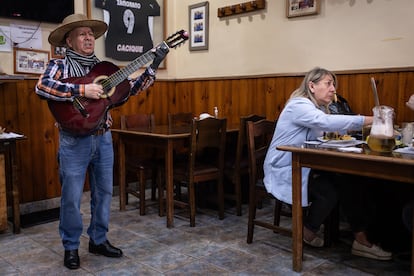 Un músico toca la guitarra al interior de El Hoyo mientras los clientes asisten a almorzar.