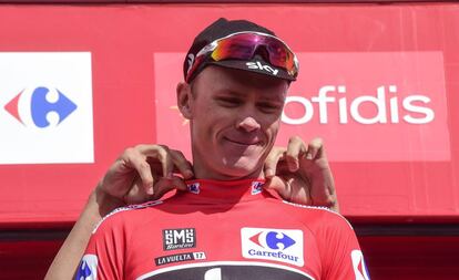 Froome sonríe en el Alto de la Mora mientras le ajustan el maillot de líder.