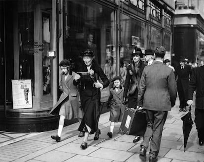 <p>Elizabeth y su hermana Margaret pasean por Londres junto a su institutriz en 1939. Hay que fijarse en sus atuendos idénticos, en el paso marcial con que caminan y en su aparente despreocupación. También en el aspecto espontáneo de la fotografía, que no hubiera desentonado en la colección de <a href="http://www.vivianmaier.com/" ref="nofollow" target="_blank">Vivian Maier</a>.</p>