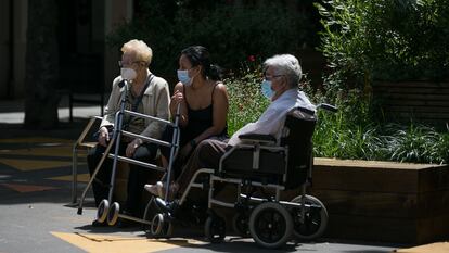 Dos ancianos junto a una joven toman el aire en el barrio de Sant Antoni, en Barcelona, el pasado junio.