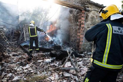 Dos bomberos sofocan un incendio en una vivienda afectada por la explosión.