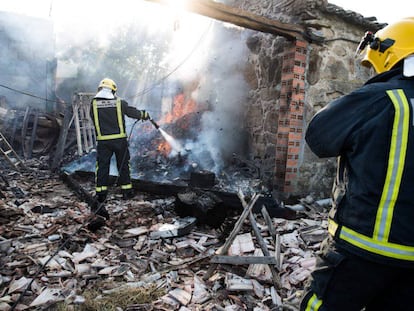 Dos bomberos sofocan un incendio en una vivienda afectada por la explosión.