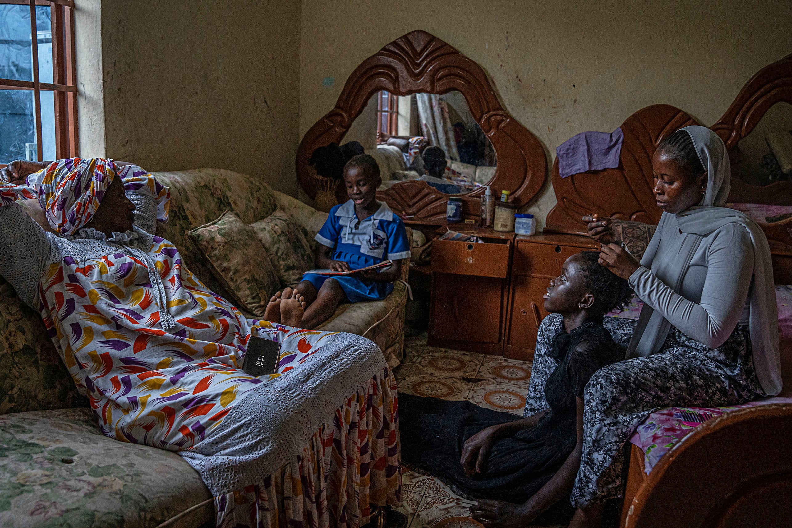 Fatou, activista contra la mutilación en programas para erradicar esta práctica de la ONG Wassu Kafo Gambia, junto a sus hijas en su casa de Brufut. 