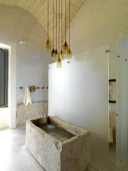 En el baño principal, un antiguo abrevadero de piedra caliza de Lecce ha sido adaptado como bañera. Del techo cuelga otra lámpara del artista del vidrio Massimo Maci.