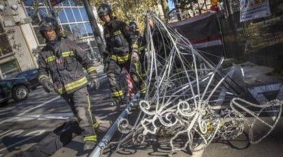 Los bomberos retiran las luces de Navidad desplomadas en el paseo de Grcia.