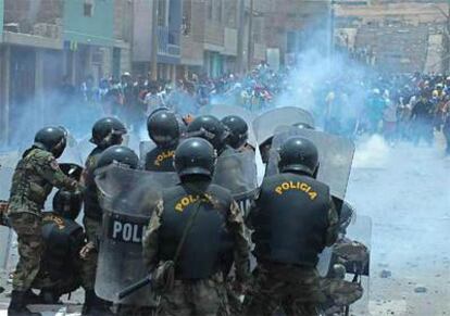 Un grupo de policías anti disturbios se enfrentan contra manifestantes en Tacna (Perú) que protestan contra la modificación de la ley del canon minero.