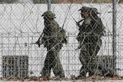 Tres legionarios pasan ante una garita junto a la valla fronteriza de Ceuta.