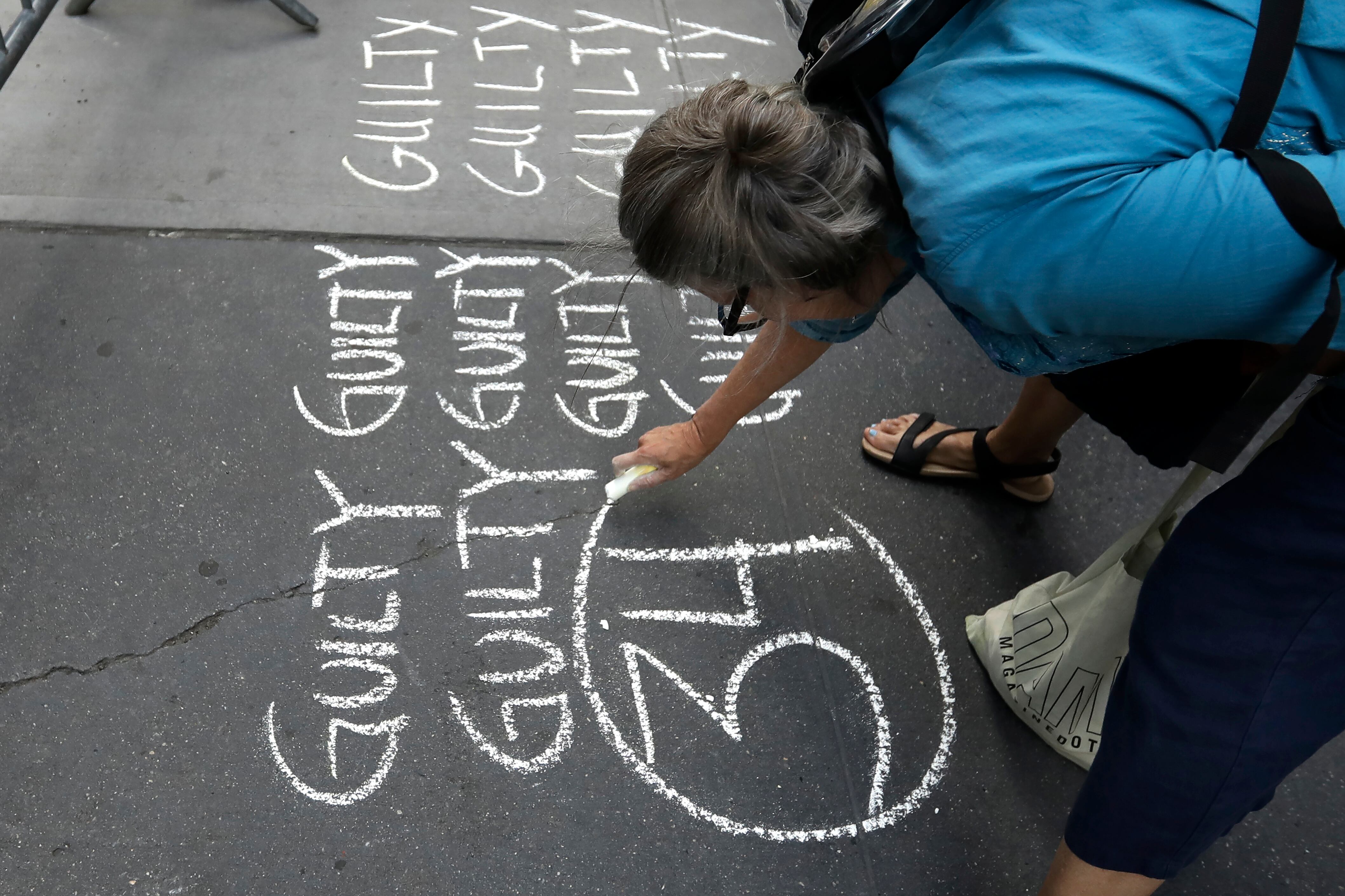 Una mujer escribe las palabras 'culpable' 34 veces con tiza en la acera frente a la Torre Trump en Nueva York, este jueves. 